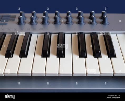 Electronic synthesizer keyboard with many control knobs on blue ...