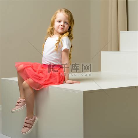 漂亮的小女孩坐在白色的楼梯上。高清摄影大图-千库网