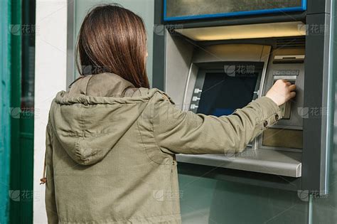 一个年轻女子从自动取款机取钱。从自动取款机里拿了张卡。金融，信用卡，取款。