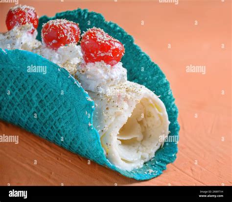 Ice cream roll of piña colada in waffle cone and cherries on orange ...