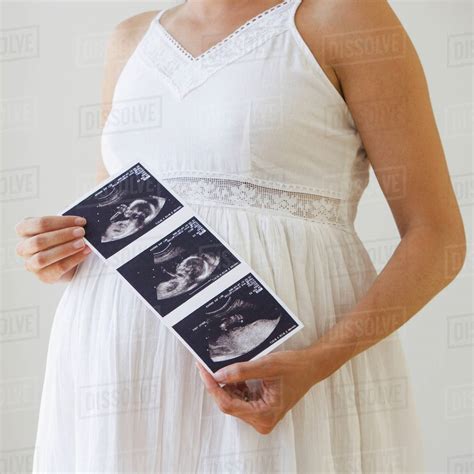 Pregnant woman holding ultrasound printout - Stock Photo - Dissolve