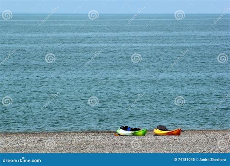 Two Colorful Sea Kayaks with Paddles and Life Jackets on Stony Beach ...
