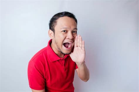 Young attractive man wearing a red tshirt shouting and screaming loud ...