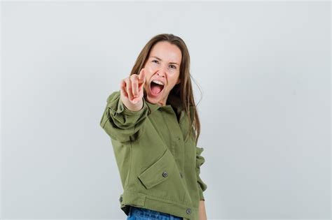 Young lady in jacket pointing at camera while screaming and looking ...