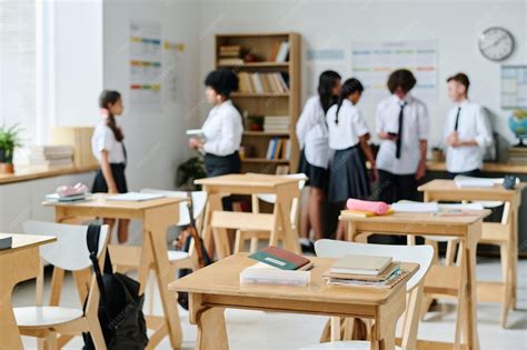 Premium Photo | Classroom with wooden desks and students talking to ...