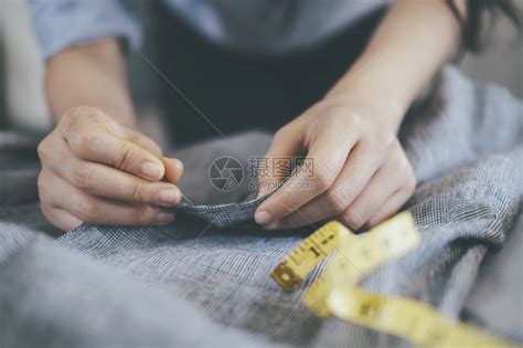 衣服工作室在桌上缝纫的年轻女裁穿着工作桌上的锯皮夹克针线活高清图片下载-正版图片307798789-摄图网
