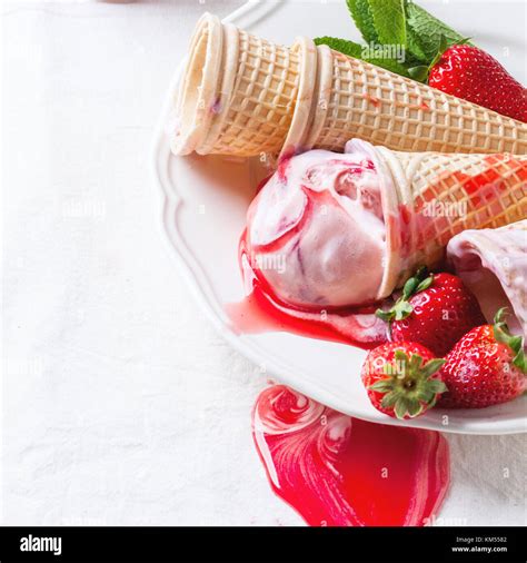 Wafer cones with strawberry ice cream with syrup, mint and fresh ...