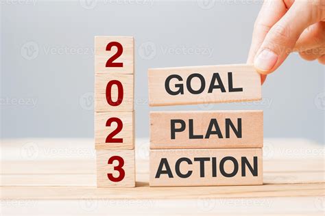 hand holding wooden block with text 2023 GOAL, PLAN and ACTION on table ...