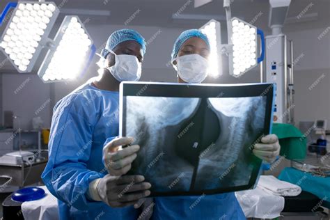 Premium Photo | African american male and female doctors with face masks looking at xrays in ...