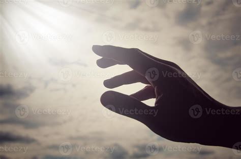 Hand reaching out to bright shining light on sky above. Religious and spiritual concept 13354322 ...