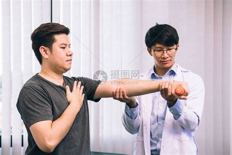 亚洲年轻男理疗师帮助病人在诊所进行举高清图片下载-正版图片506711335-摄图网