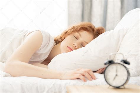 甜美的女孩躺在床上，在毯子下，她的头在枕头上，而做梦前几分钟报警高清摄影大图-千库网