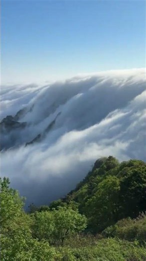 Cloud waterfall flows over mountain ridge at Daheishan scenic area in Dalian, China