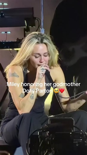Miley Cyrus turned “Jolene” into an emotional tribute to her godmother, Dolly Parton 🥹❤️‍🔥 With Dolly’s image projected behind her at the Hollywood Bowl, this was more than a cover — it was a moment honoring a legend and their special bond. 🎤✨ Dolly Parton’s “Jolene” tells the story of a woman pleading with a rival not to take the man she loves. Miley Cyrus brings her own emotional depth to the country classic, turning the performance into a heartfelt tribute to her godmother and one of count