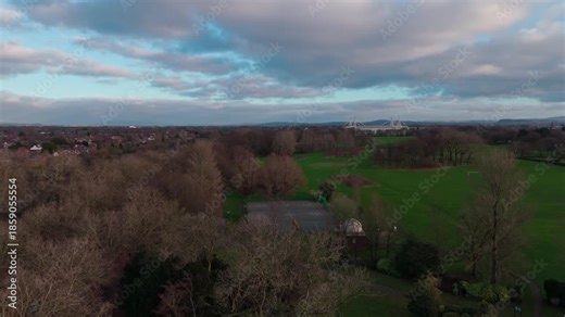 Aerial view rising up over Moor park in Preston, England, showing trees, sports field and footbal stadium