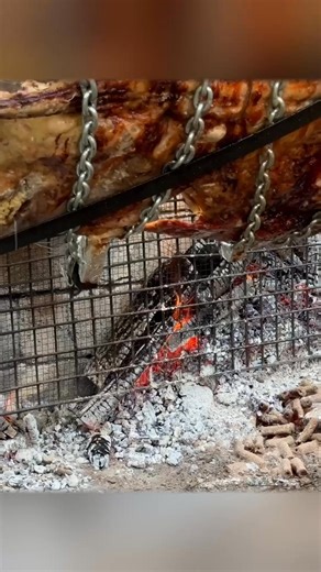 Tender meat roasting over an open fire, basted with flavorful liquid, then sliced for serving. #OpenFireCooking #RoastedMeat #OutdoorCooking #Cooking | Wilderness Grill