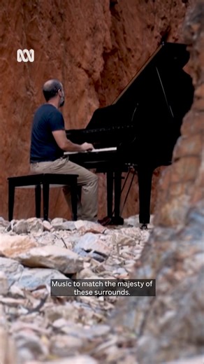 At the bottom of towering red rock walls bathed in a dramatic orange glow, a very special piano performance has taken place in the remote Australian outback. The surprise sunrise concert in Standley Chasm, 50 kilometres west of Alice Springs, left passers-by in awe, but getting the grand piano in was no easy feat. 🎤 Victoria Ellis #ABCNewsNT | ABC Darwin