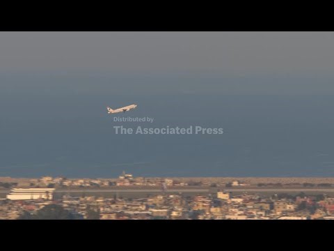 A commercial airplane takes off amid smoke and explosions in Beirut