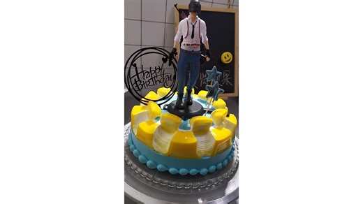 Decorating yellow and blue cream cake with PUBG character topper creating gaming theme birthday dessert