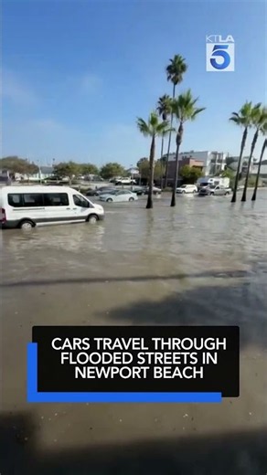 Cars travel through flooded streets in Newport Beach