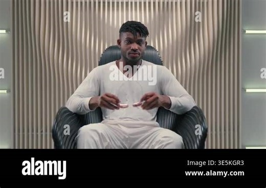 Confident African American guy man putting on stylish brown glasses sunglasses eyewear wearing trendy modern eyeglasses sitting in chair in futuristic room futurism studio cyber male looking at camera Stock Video Footage - Alamy