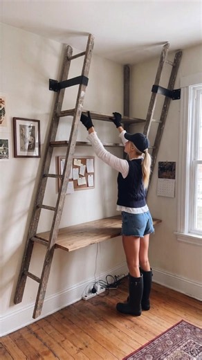 The best vertical storage hack for small desks… Anchored vintage wooden painter ladders to the wall with heavy-duty metal brackets, slotted reclaimed timber planks across the rungs, and built a custom floating ladder shelf over the workspace.