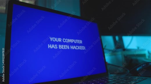 Computer screen in dark office is hacked remotely with alert message on screen. Glitch and error notification or warning of cyber attack taking control of laptop on desk. Hacker group stealing data