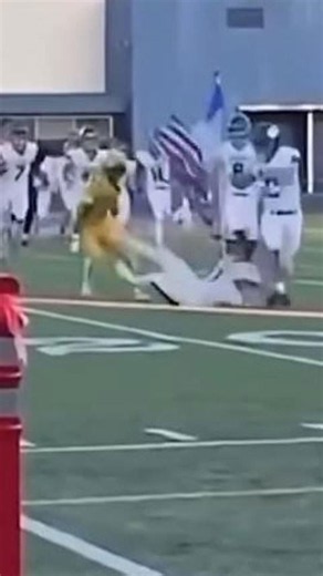 Football player slams into rival carrying an American flag