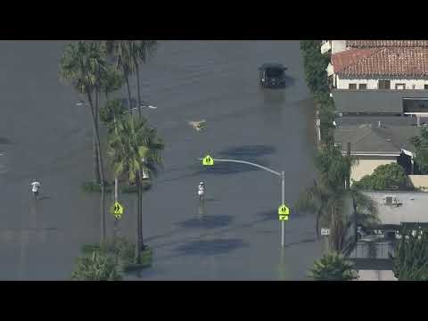 Person seen riding surfboard through high floodwaters in Newport Beach