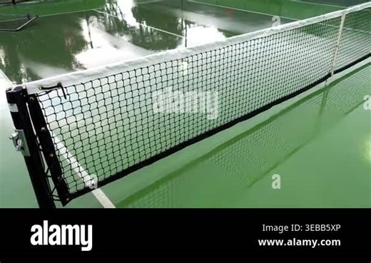 Empty outdoor pickleball courts glistening with rainwater and reflections after a recent storm, showing the net, wet surface, and surrounding fence with no players present on the court Stock Video Footage - Alamy