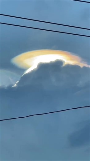 Today in Indramayu, a coastal city in West Java, Indonesia, a clear sky was seen with a striking iridescent cloud formation (pileus cloud) above a street scene.(May 05)