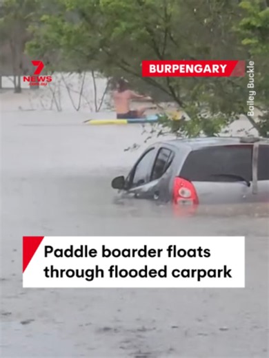 A shirtless man has been spotted floating on a paddleboard through a flooded carpark north of Brisbane, past a partially submerged vehicle in Burpengary. Storm warnings have been cancelled for now but flood warnings remain current in Southeast Queensland. #kayak #flood #emergency #burpengary #queensland