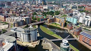 Aerial drone footage of the area in the Leeds City Centre known as The Leeds Dock, showing apartments and buildings along side the River Aire and canal on a bright sunny summers day