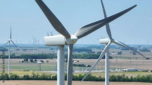 Close up of multiple propellers spinning at top of wind turbine with slow zoom in aerial video