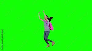 Slow motion of happy female high school student jumping while carrying backpack in the studio with green screen background