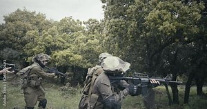 Squad of fully armed commando soldiers during combat in a forest scenery