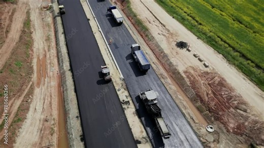 Aerial view of construction equipment building an automobile highway. Heavy equipment, rollers rolling out a new layer of asphalt. 4k footage