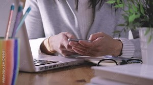 working at home, smart working. woman is set down and uses smartphone and laptop on desk. Girl uses many technological device for communicate and work.