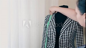 Woman designer women's clothing makes a measurement on a black and white jacket 1080