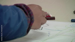 Kindergarten Boy Making a Drawing using Different Crayons in Classroom. Close Up.