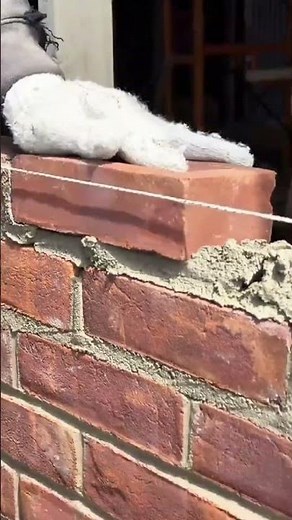 Arranging red bricks neatly using cement and a leveling tool to build a solid wall structure