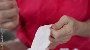 asian senior woman using thread picker removing thread on clothes for repairing.