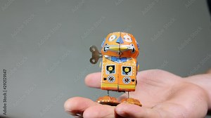 4K man holding vintage tin wind up walking robot toy