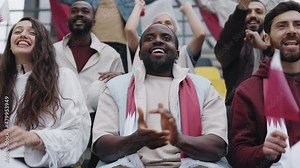 Positive fan clapping and smiling while watching soccer game