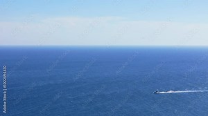 Aerial view of frigate birds soaring high above the Curacao coastline as boat drives by, with the blue skies and ocean below creating a serene landscape
