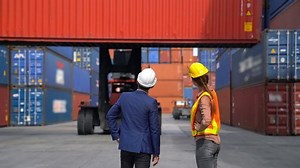 Engineer woman with Business man control loading Container from Cargo freight ship for import and export , support logistics transportation concept.