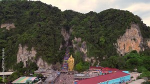 Hindu giant cave Batu golden Buddha statue Smooth aerial top view flight drone