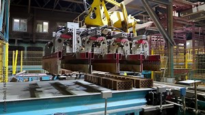 Brick production line with robotic weapons in a modern bright factory. Bricks for construction are collected on a conveyor belt.