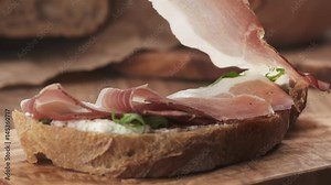Slow motion of italian speck put on rustic bread with arugula and ricotta cheese, 180fps prores footage