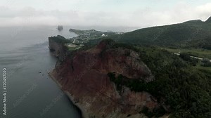 Rocky Cliffs Of Gaspe Peninsula With The Lush Green Forest And Overlooking The Perce Rock On The Distance On A Foggy Day In Quebec, Canada. -aerial drone